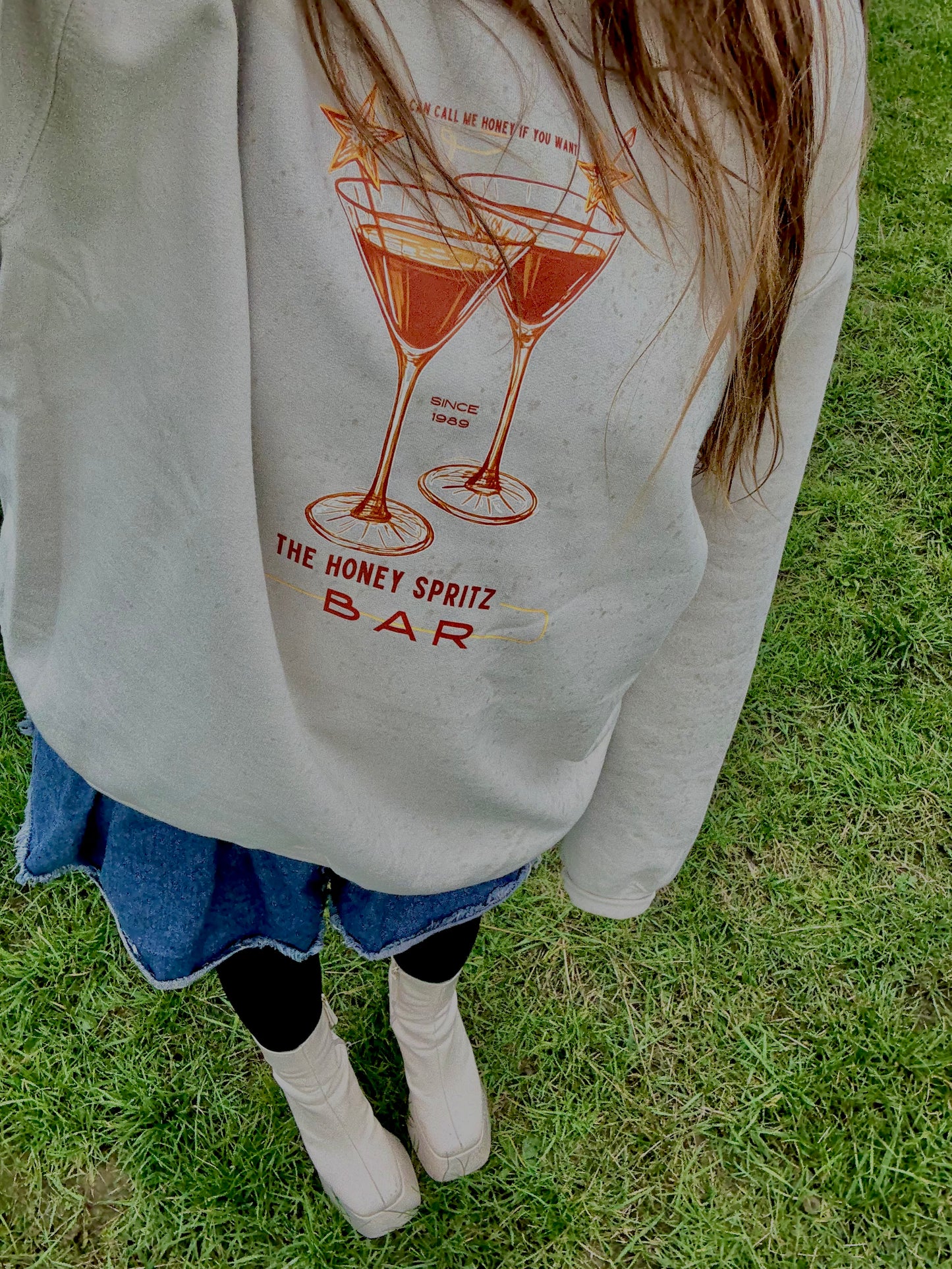 Person wearing a sweatshirt with a graphic design on grass

