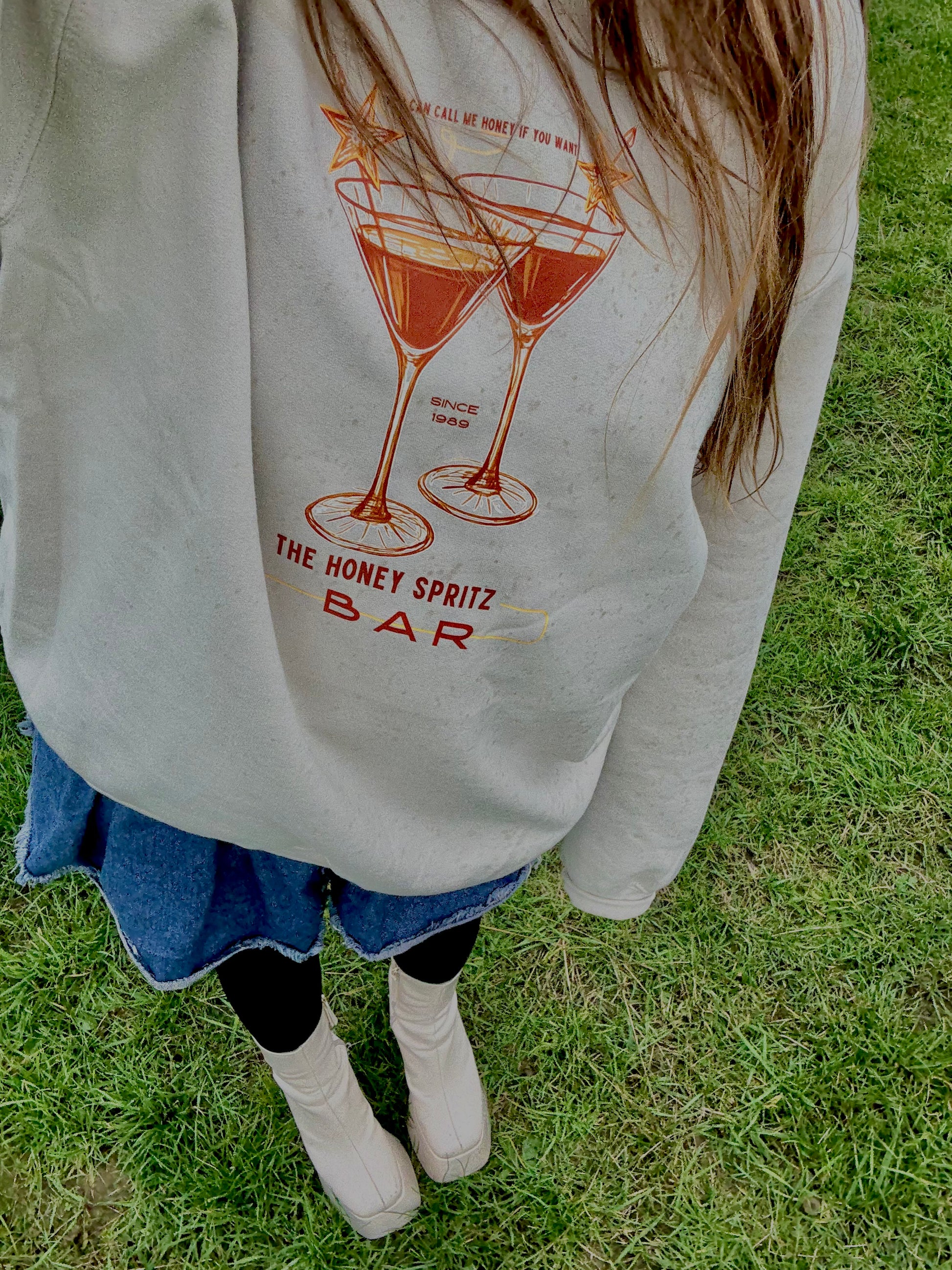 Person wearing a sweatshirt with a graphic design on grass

